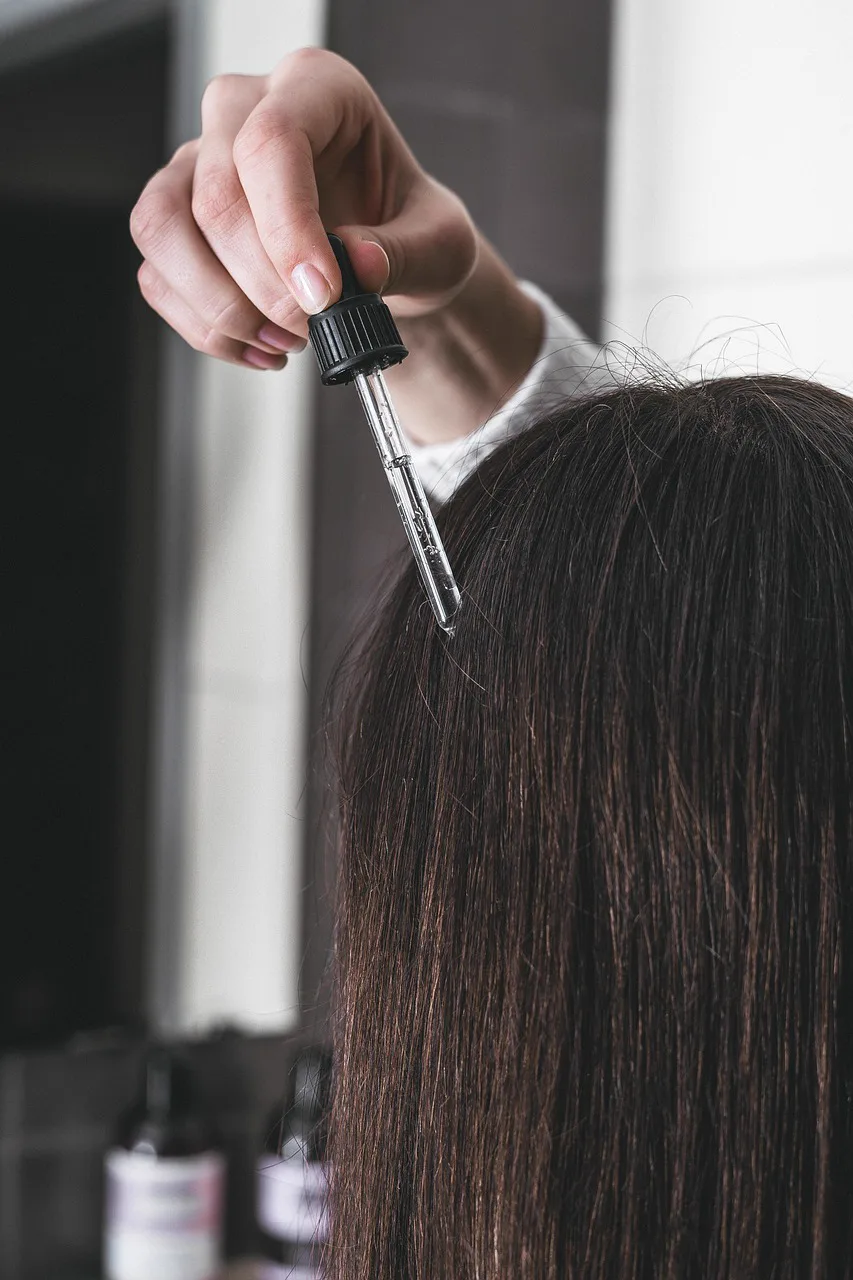 Serum being applied to the hair and scalp with a dropper